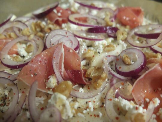 Der frisch belegte Flammkuchen ist startbereit für den Ofen